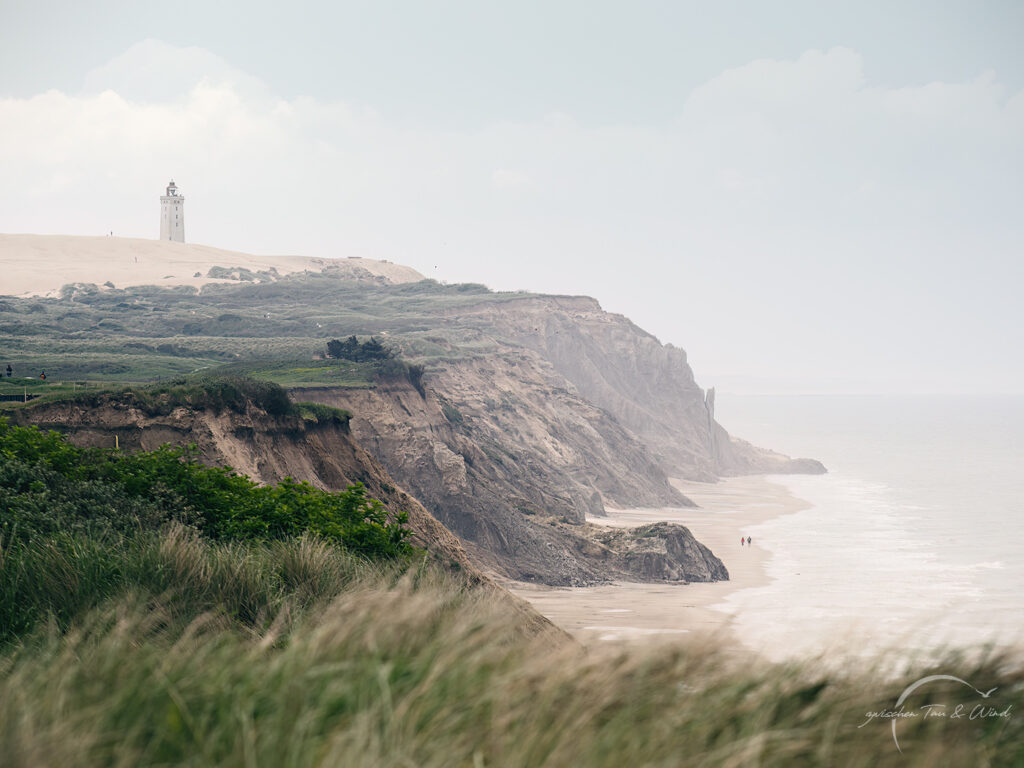 Zwei Wanderer unter dem Rubjerg Knude Fyr. Kontemplative Fotografie aus dem Projekt "Zwischen Tau und Wind" von Katrin Jeschke