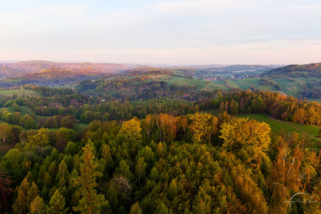 Sonnenaufgang auf dem Weifbergturm. Blick auf die Hintere Sächsische Schweiz im goldenen Morgenlicht. Kontemplative Fotografie aus dem Projekt "Zwischen Tau und Wind" von Katrin Jeschke