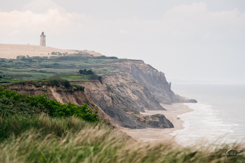 Zwei Wanderer unter dem Rubjerg Knude Fyr. Kontemplative Fotografie aus dem Projekt "Zwischen Tau und Wind" von Katrin Jeschke